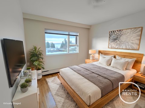 A bedroom with a large bed, a flat screen TV, and a window overlooking a snowy landscape.