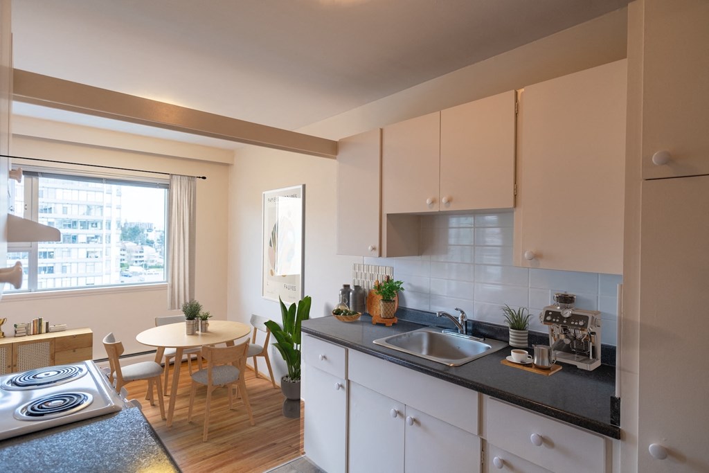 A modern kitchen with white cabinets and a black countertop.
