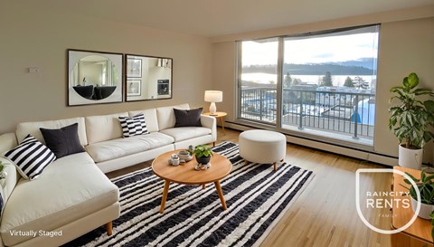 A living room with a white couch, a coffee table, and a large window overlooking a snowy landscape.