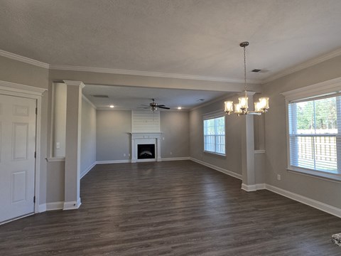 an empty living room with a fireplace and a ceiling fan