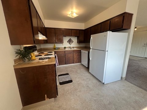 A kitchen with brown cabinets and a white refrigerator.