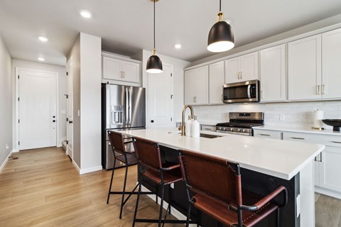 a kitchen with white cabinets and a large island with chairs