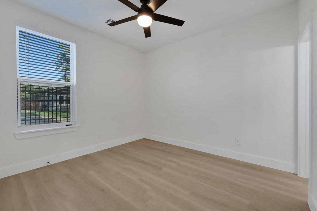 an empty living room with a window and a ceiling fan