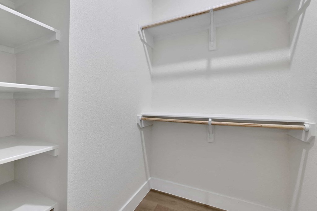 a walk in closet with white walls and shelves and