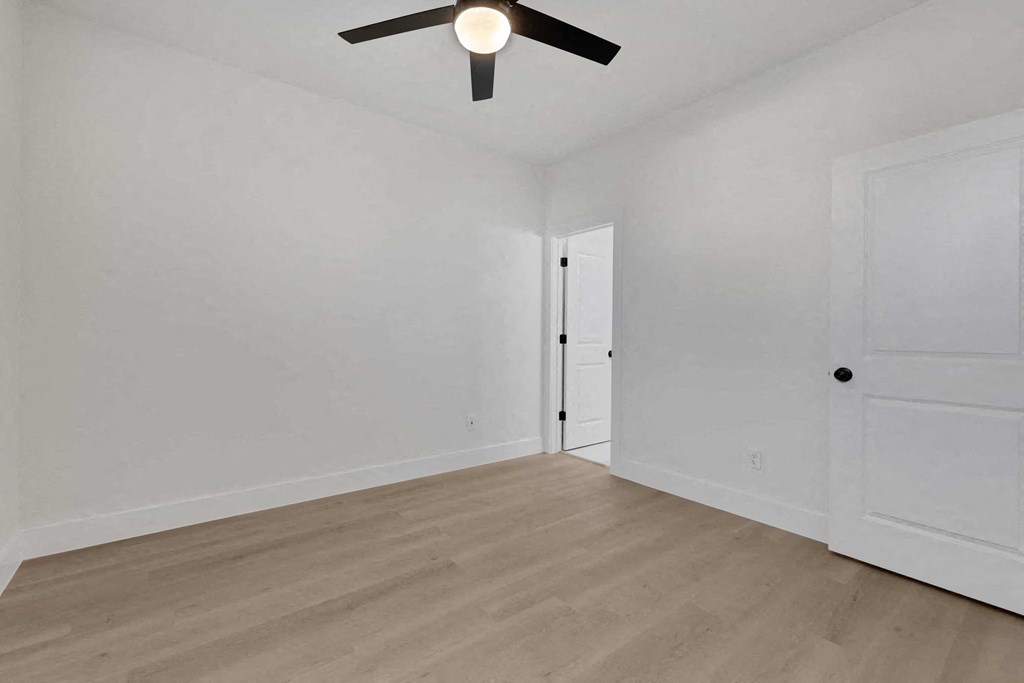 a living room with white walls and a ceiling fan