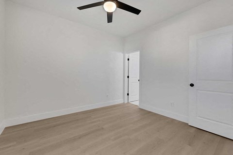 a living room with white walls and a ceiling fan