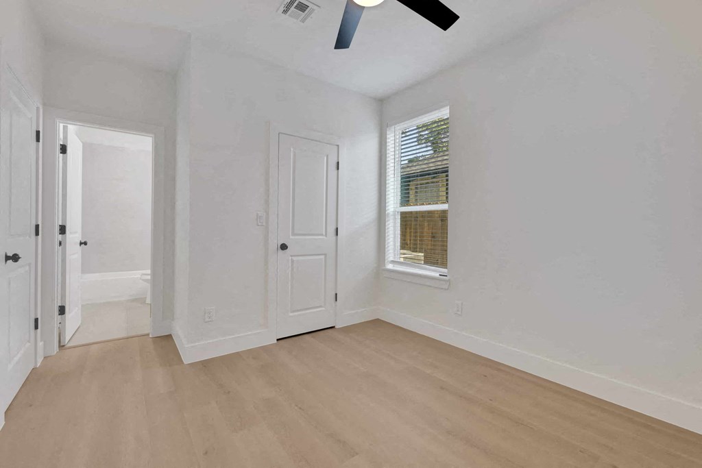 a living room with white walls and a window and wooden floors