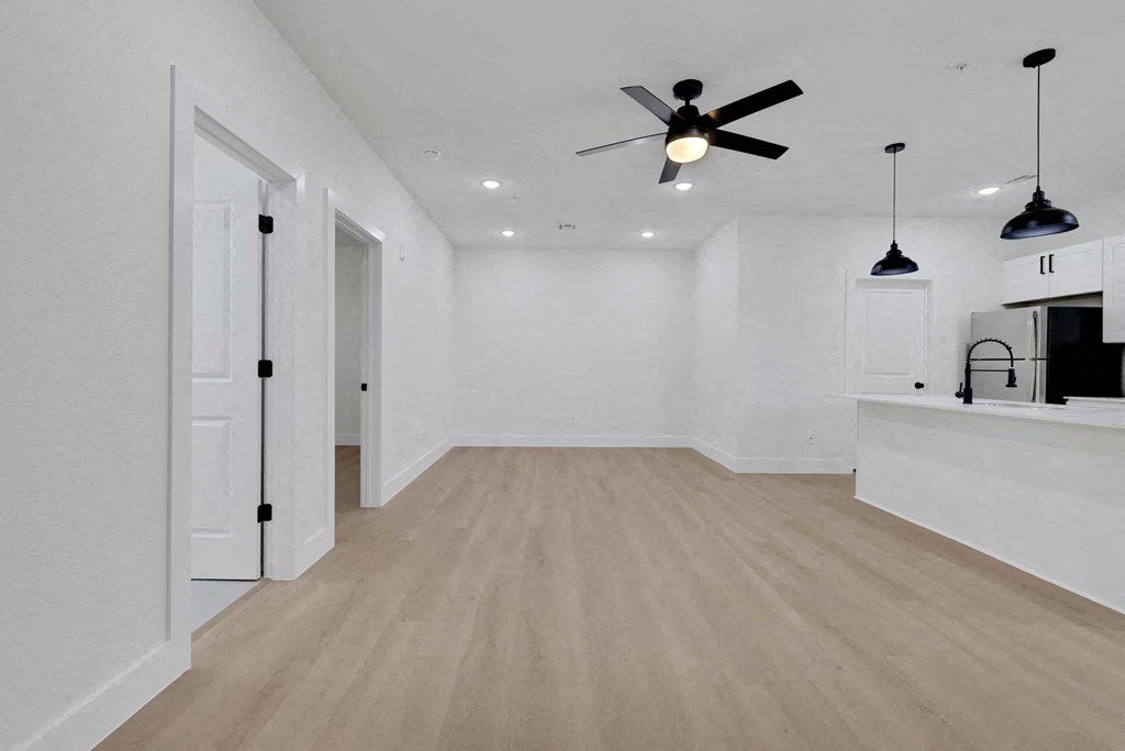 a living room with white walls and a ceiling fan