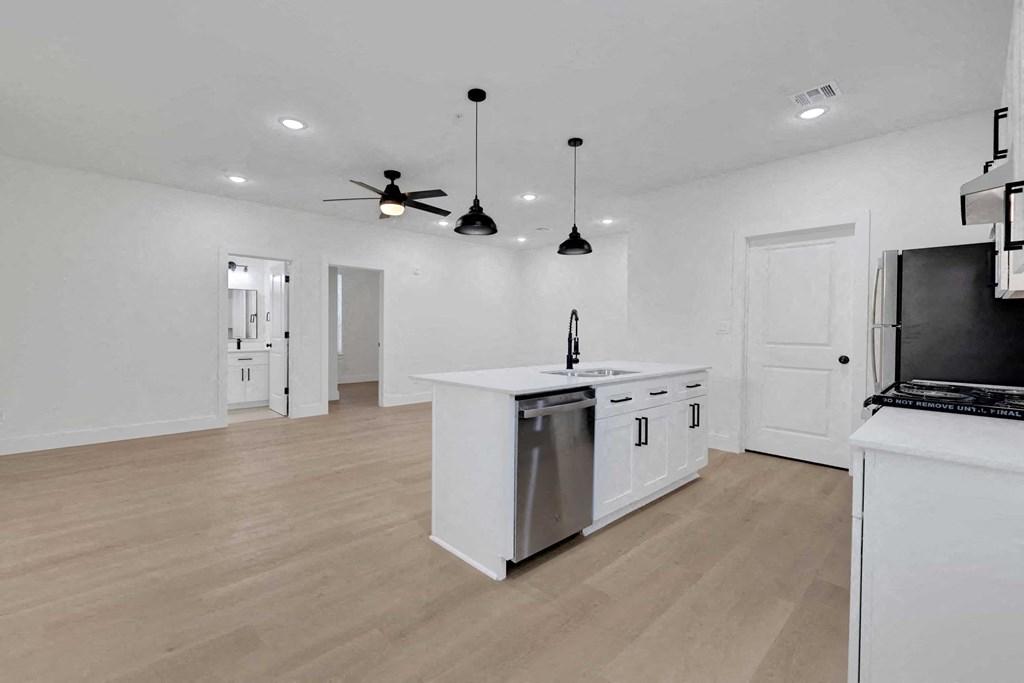 a white kitchen with an island and a ceiling fan
