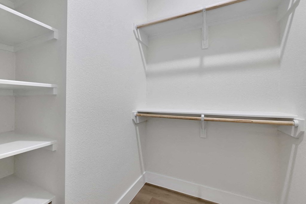a walk in closet with white walls and shelves and