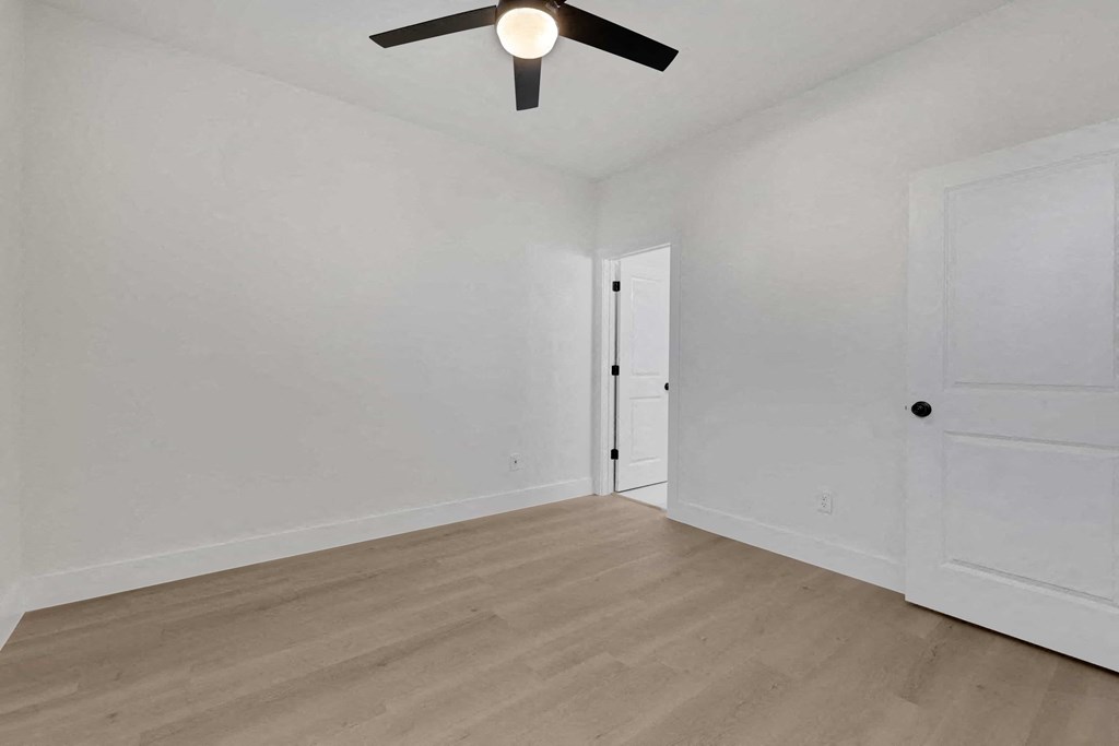 a living room with white walls and a ceiling fan
