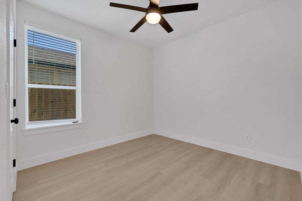 an empty room with a window and a ceiling fan