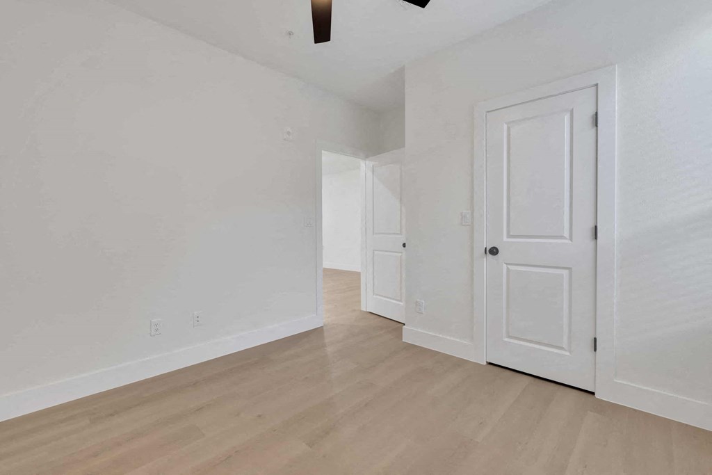 a bedroom with white walls and wood flooring and a white door