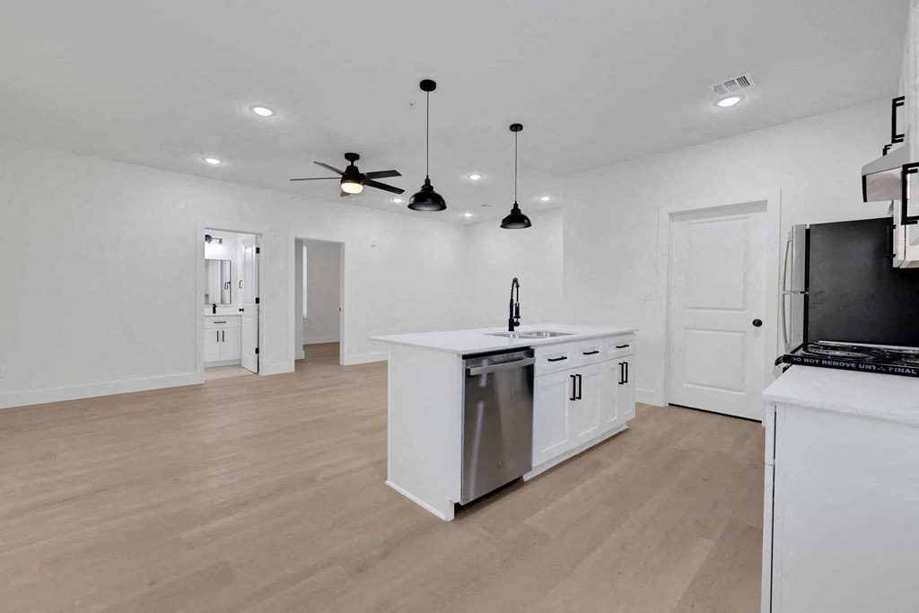 a white kitchen with an island and a ceiling fan