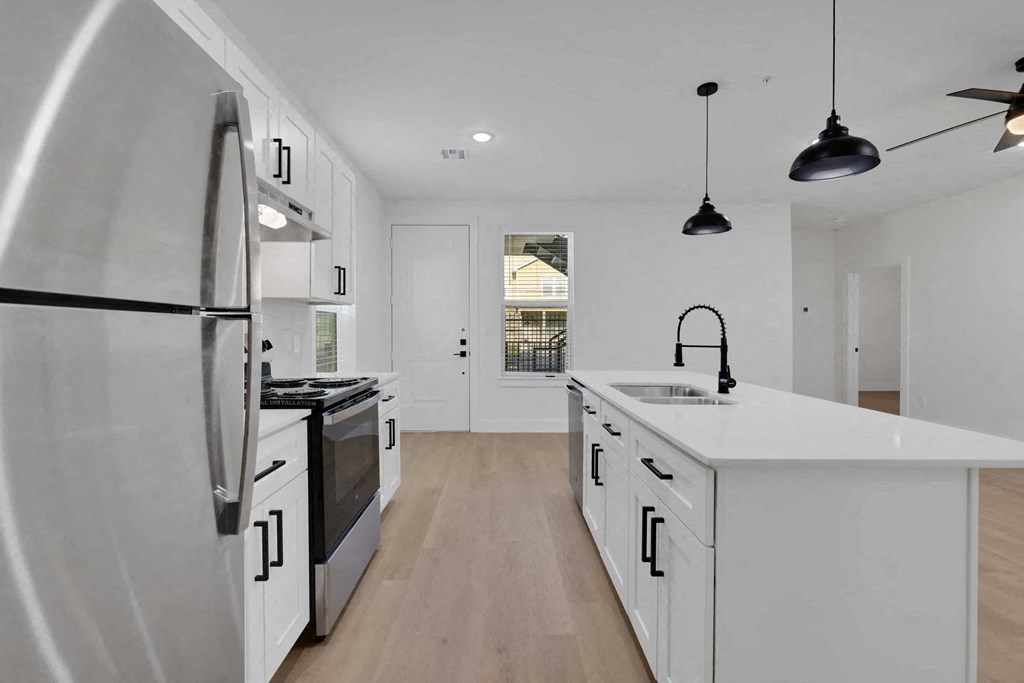 a white kitchen with an island and a refrigerator