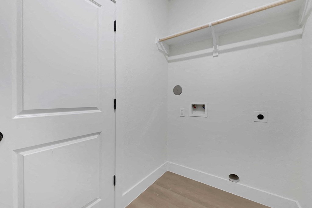the closet in a bedroom of a home with white walls and wood floors