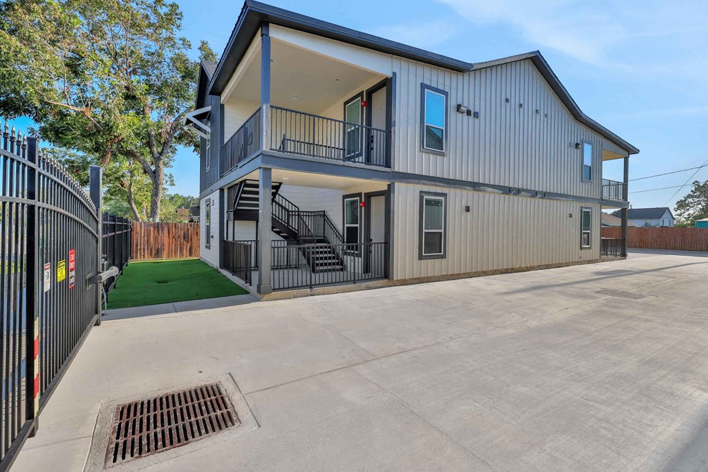 the front of a house with a driveway and a fence