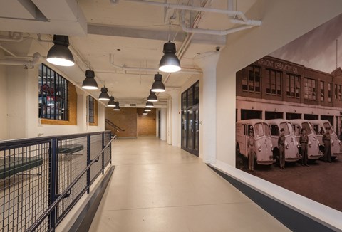 A long hallway with a rail on the left and a picture of cars on the right.
