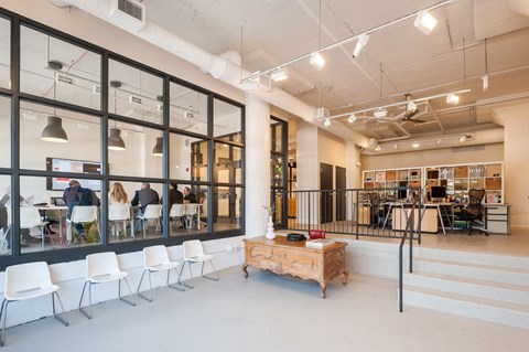 A room with white chairs and a wooden table with a red book on it.