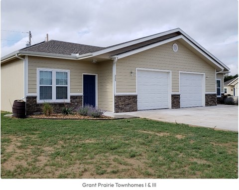 a tan house with two garage doors and a driveway