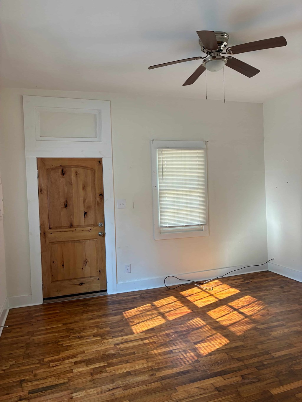 A room with a wooden floor and a ceiling fan.
