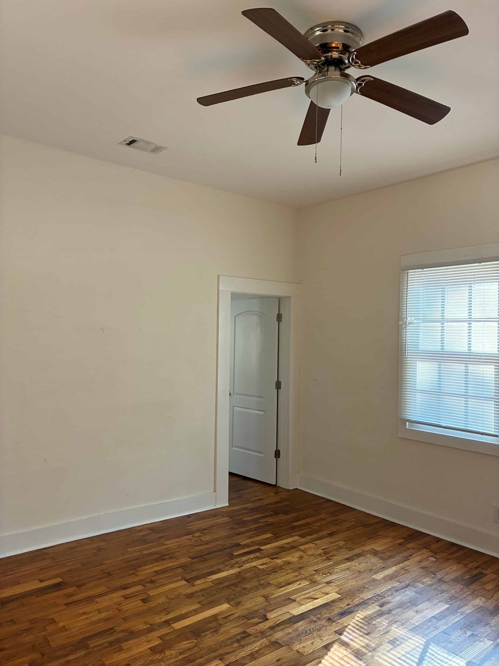 A room with a ceiling fan and wooden floors.