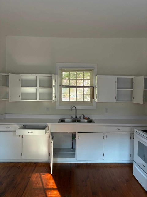 A kitchen with white cabinets and a window.