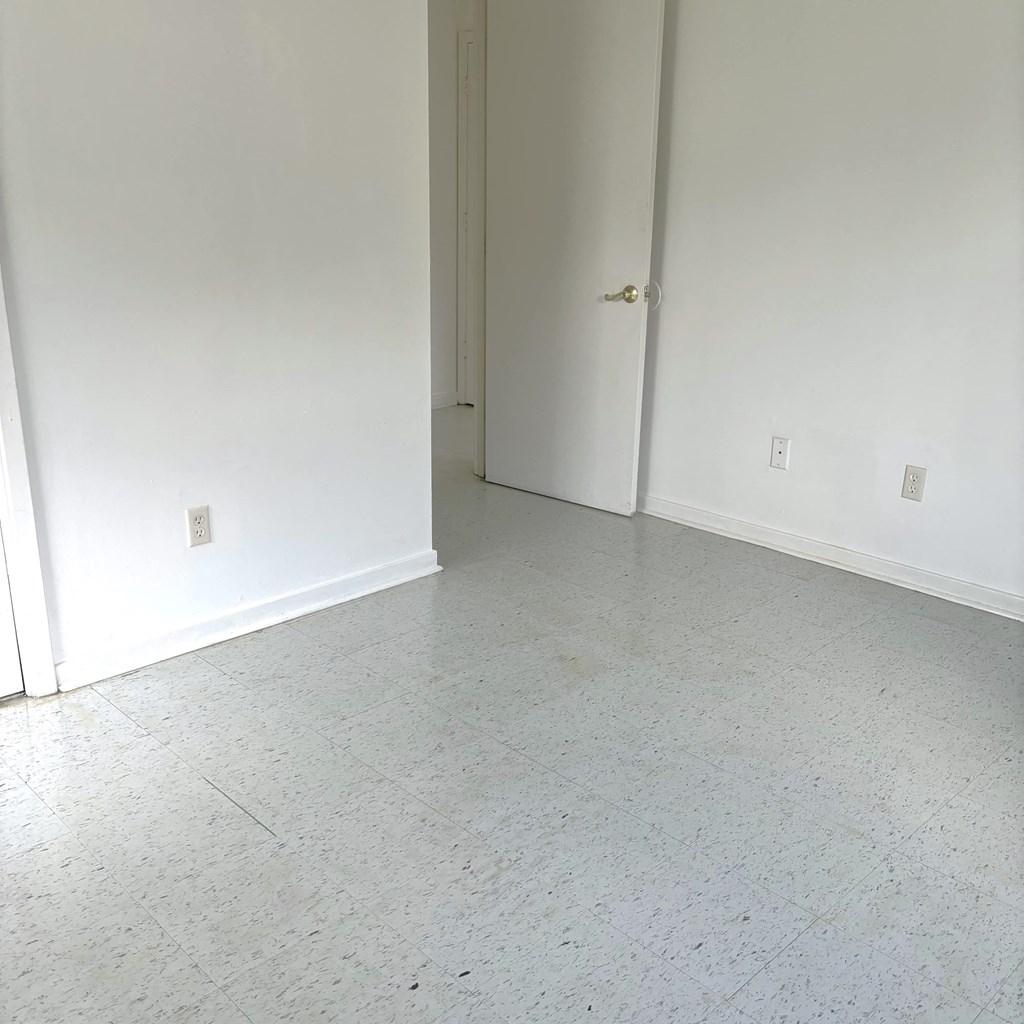 an empty living room with white walls and a tile floor