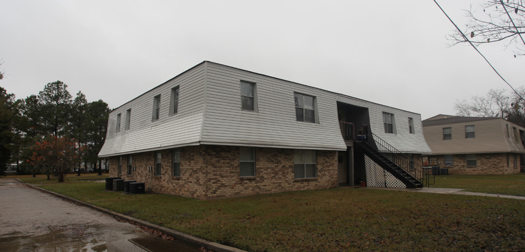 a white house with a white roof and a stone wall