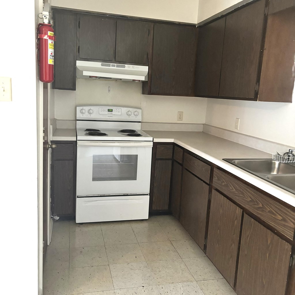 an empty kitchen with white appliances and wooden cabinets