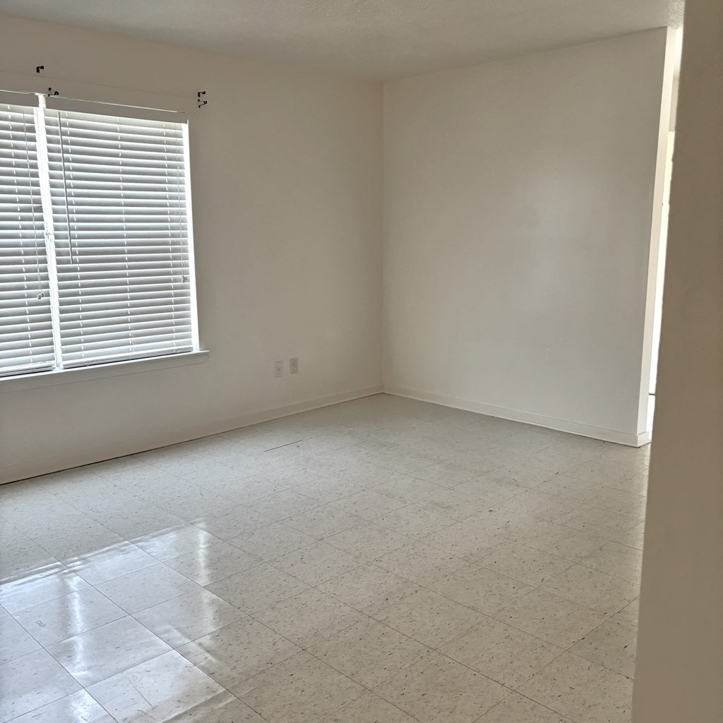 an empty room with a window and a tiled floor