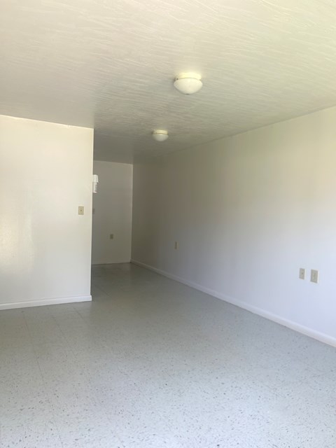 an empty living room with white walls and a ceiling light
