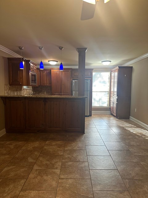 A kitchen with brown cabinets and tile flooring.