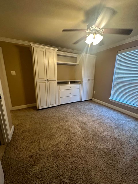 a bedroom with white cabinets and a ceiling fan