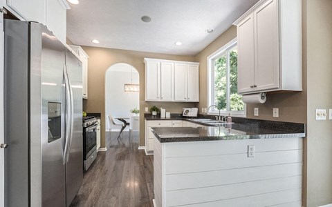 a kitchen with white cabinets and a stainless steel refrigerator
