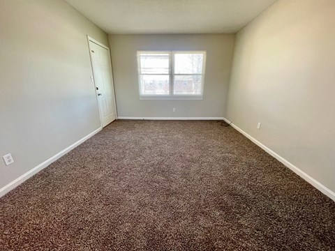 A room with a brown carpet and a window.