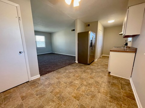 A kitchen area with a refrigerator, cabinets, and a countertop.
