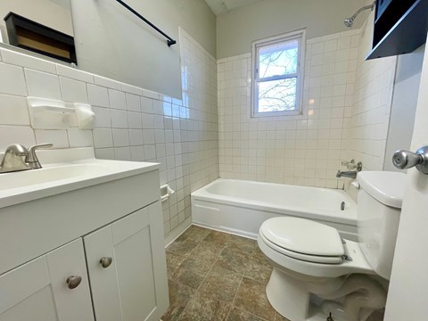 A white bathroom with a toilet, sink, and bathtub.