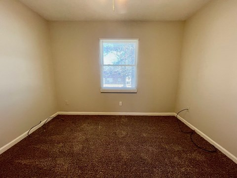 A room with a window and carpeted floor.