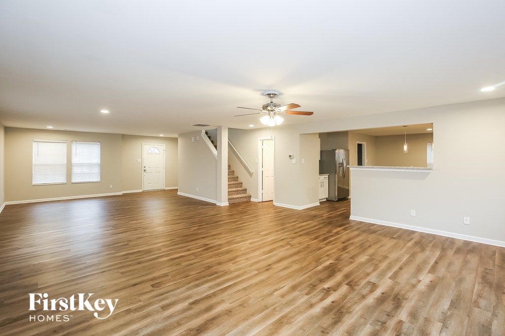 A spacious room with wooden floors and a staircase leading to another room.
