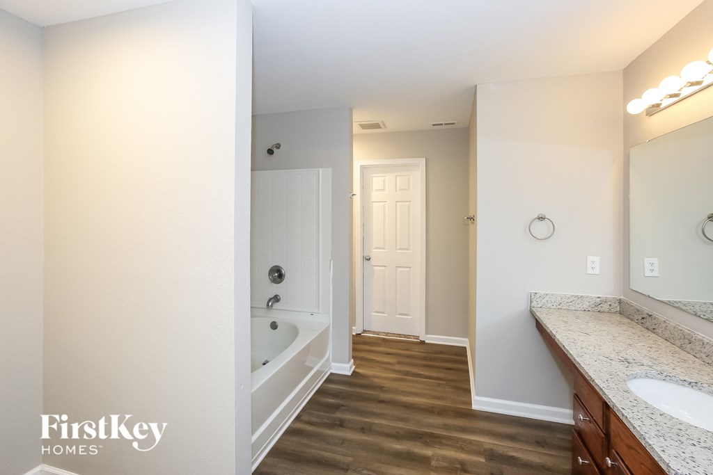 A bathroom with a wooden floor and white walls.