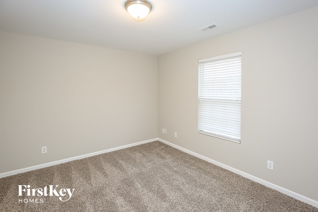 A room with a carpet floor and a window with blinds.