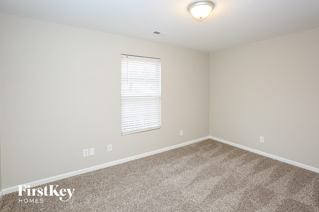 A room with a carpeted floor and a window with blinds.