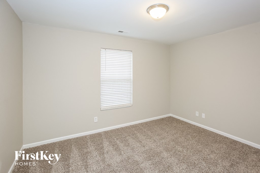 A room with a carpeted floor and a window with blinds.
