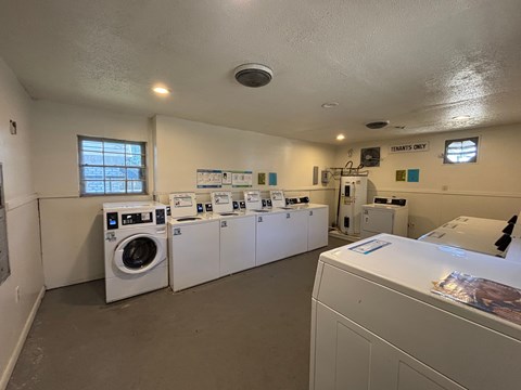 A laundromat with a row of washers and dryers.