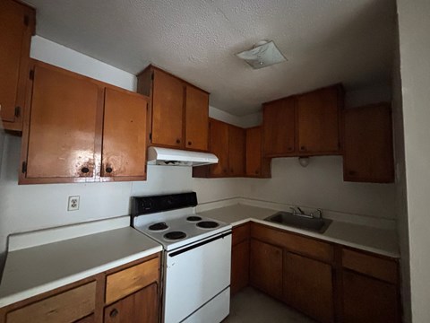A kitchen with wooden cabinets and a white stove.