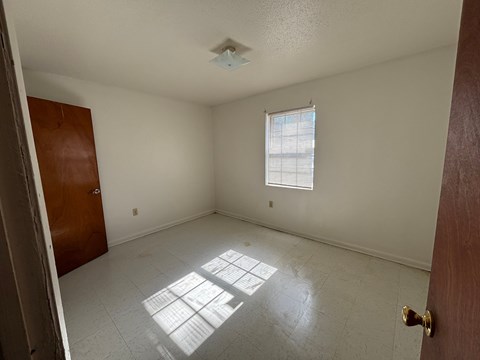 A room with a door, window, and a ceiling fan.