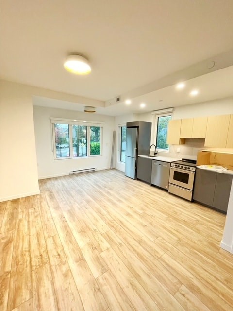 an empty living room and kitchen with wood floors