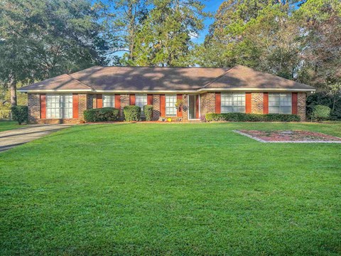 a small brick house with a lawn in front of it