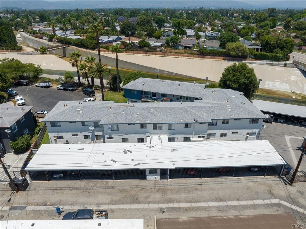 A large building with a grey roof is surrounded by a parking lot and other buildings.